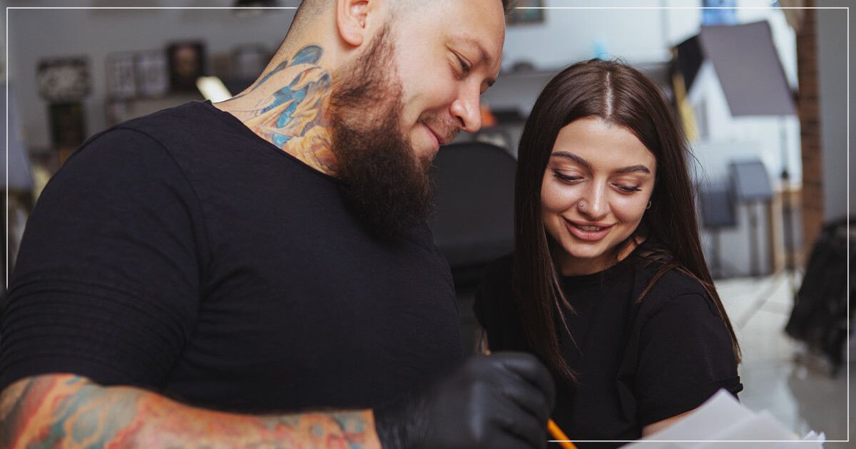 Tattoo artist showing female client tattoo concept.