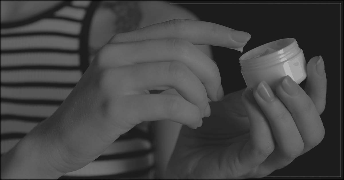 Woman dipping finger in moisturizer