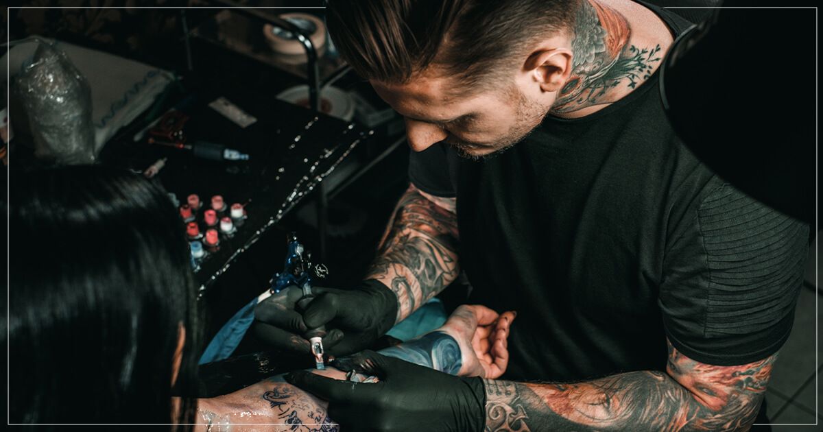 Male tattoo artist tattooing client.
