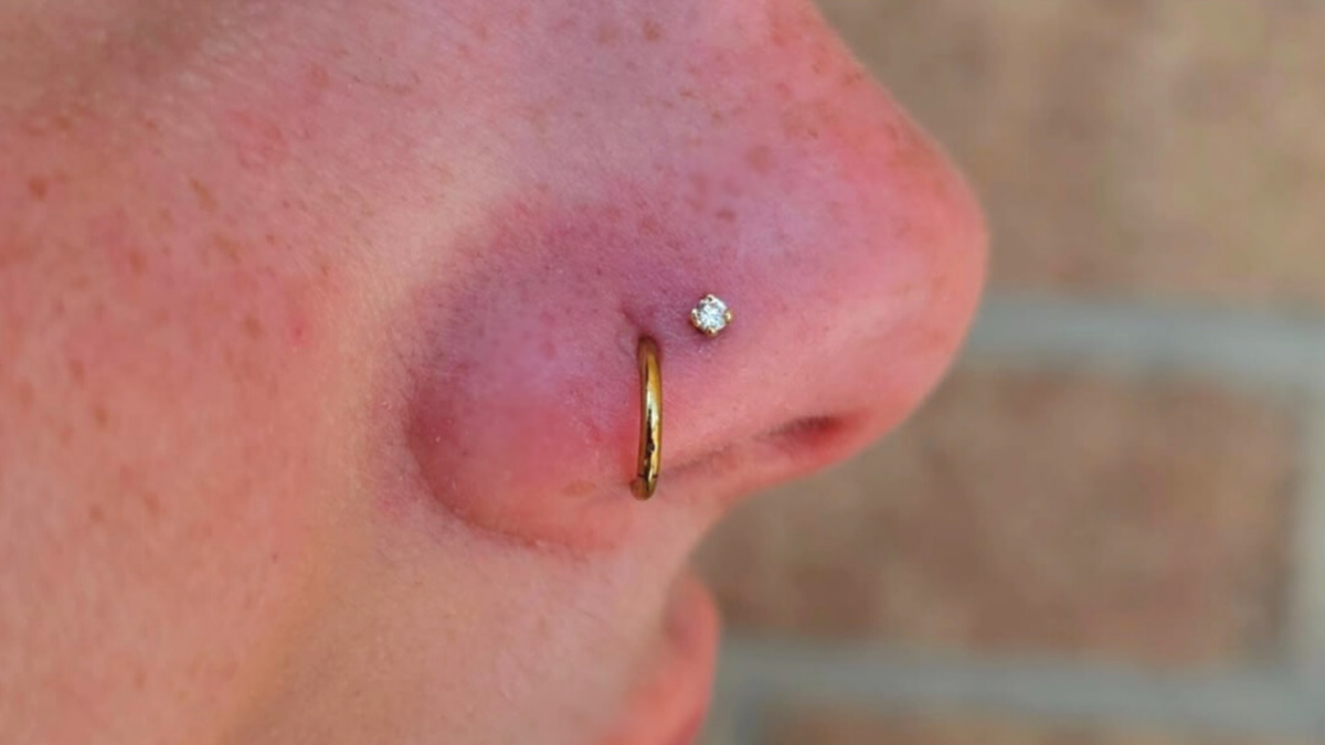 A healed nostril piercing with a small flat backed stud and a clicker ring